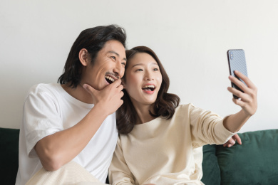 年轻情侣坐在沙发上用手机自拍