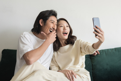 年轻情侣坐在沙发上用手机自拍