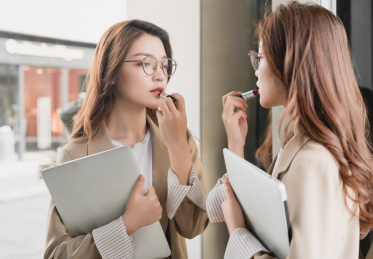 年轻亚洲商务人士对着镜子补妆画口红