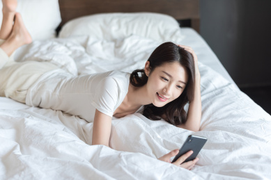 在床上使用手机的年轻女性