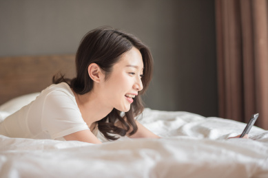 在床上使用手机的年轻女性