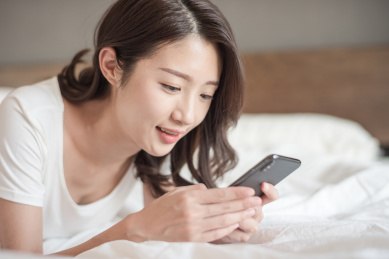 在床上使用手机的年轻女性