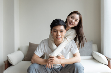 一对年轻的亚洲情侣在沙发上互相拍照