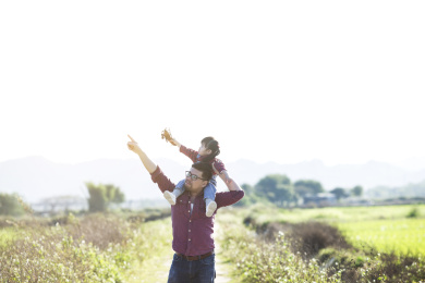 一位父亲带着女儿在田野玩耍