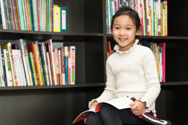 坐在书架前认真读书的中国女孩