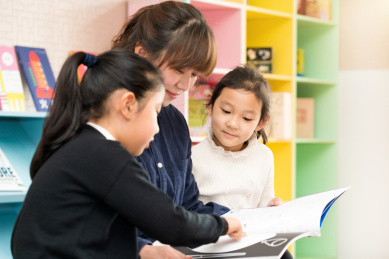 年轻的母亲陪伴两个孩子阅读书籍