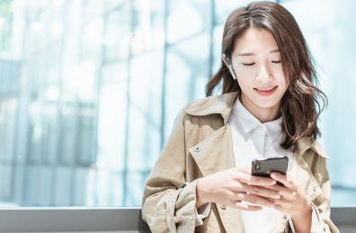 亚洲商务人士靠在窗边栏杆低头看手机