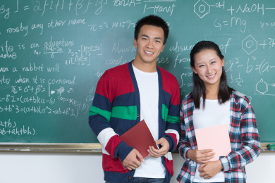 男女大学生站在黑板前合影