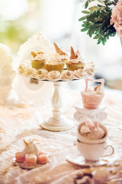 白瓷餐具上摆放着杯子蛋糕和马卡龙。