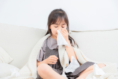  坐在沙发上的亚洲小女孩，身体感觉不舒服