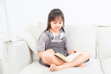坐在沙发上看书的亚洲小女孩