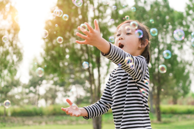 在草坪上玩吹泡泡游戏的女孩