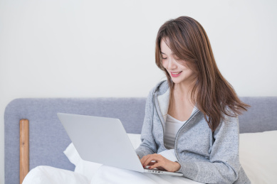 年轻女性在床上使用电脑工作