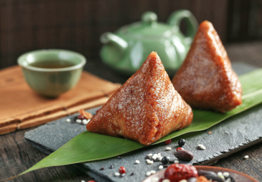 剥开的粽子放在绿色粽叶上