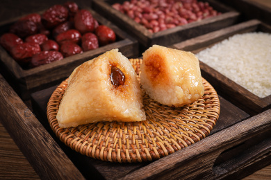 放在木盘里竹垫上切开的蜜枣粽子