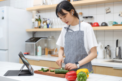  边切菜边玩平板电脑的清纯女孩
