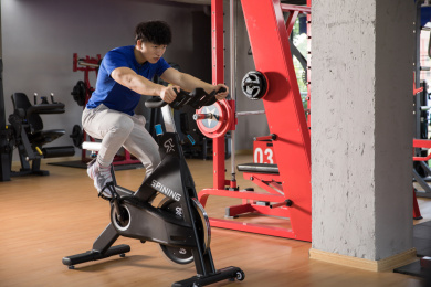 在健身房里踩单车锻炼的年轻男性