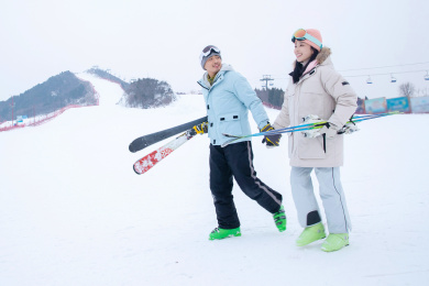 青年伴侣手牵手拿着滑雪板边走边聊