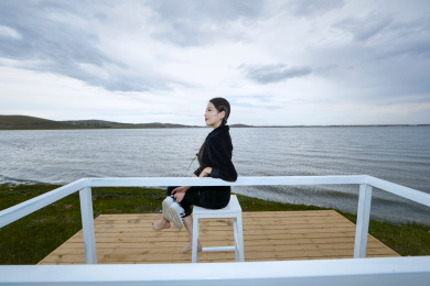 悠闲的坐在美丽湖岸码头的梳双马尾的少女