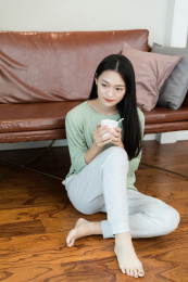长发女生坐在沙发前抱着水杯