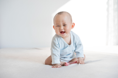 坐着嬉笑的九个月婴儿