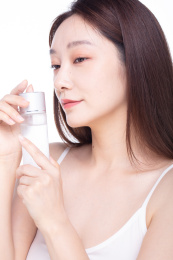 白色背景前使用护肤品的女性