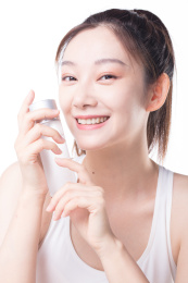 白色背景前使用护肤品的女性