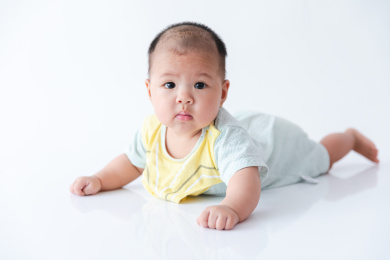 一百天大的宝宝一个人在纯白的背景里趴着玩
