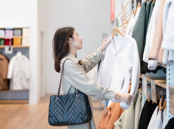 在商店内拿着外套挑选冬季衣服的女士