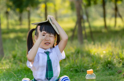 坐在草地上看书的亚洲小女孩