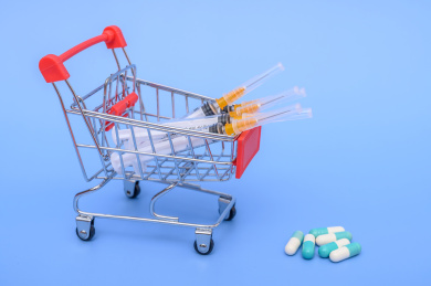 蓝色背景前的购物车和注射器购买疫苗概念