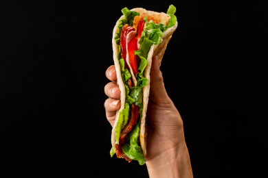 黑色背景里一只手抓着的手抓饼