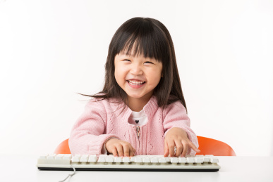 操作电脑键盘的亚洲小女孩非常开心
