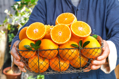 手上端着一筐冰糖橙和切面橙子