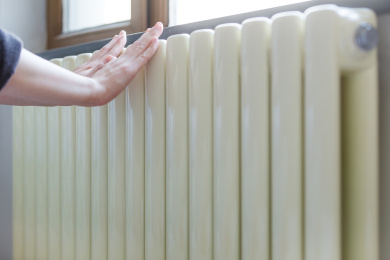 冬季北方开始供暖，把手放在暖气上取暖。