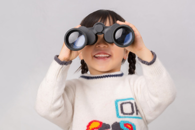 小女孩手拿望远镜看向镜头