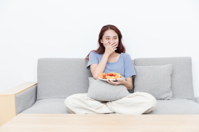 年轻居家女性拿着水果看电视