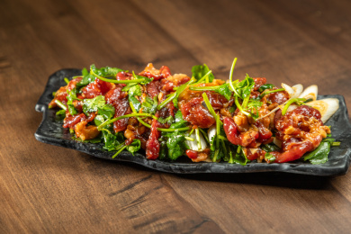 棕色木纹桌上放着一盘秘制手切鲜羊肉