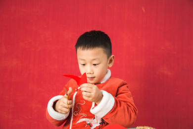 亚洲中国男孩过年在红背景室内穿红棉袄大笑