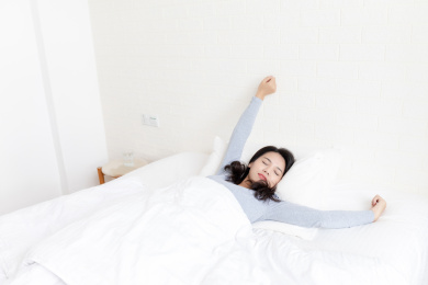 卧室里一名刚起床的年轻女性在伸懒腰