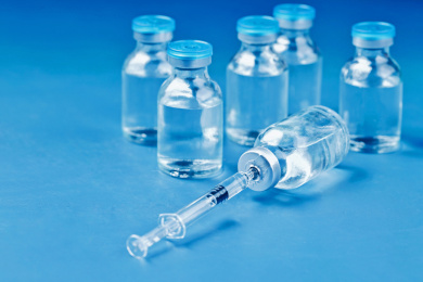 疫苗注射器和玻璃药瓶在蓝色背景上