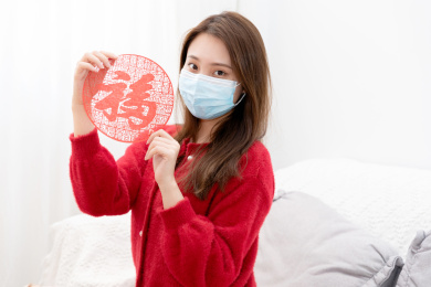 穿红色毛衣的女孩戴着口罩手拿福字剪纸