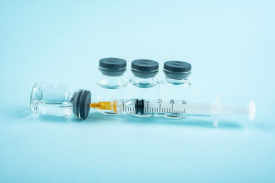 蓝色背景上的疫苗和注射器