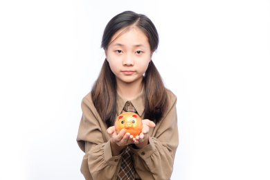 白色背景里，拿着存钱罐的亚洲小女孩