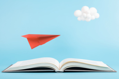 蓝色天空书本上飞翔的纸飞机与可爱的云朵