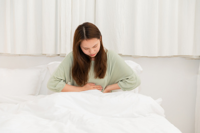 女生肚子疼坐在床上表情痛苦