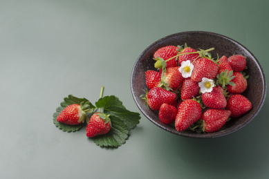 黑色斗笠碗里的草莓及桌面上两个散落草莓