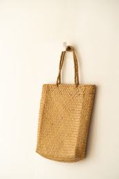 竖构图，挂在暖黄色墙壁上的编织袋