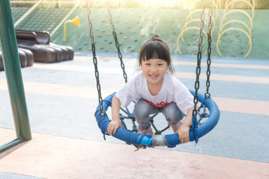 游乐场里玩秋千的亚洲小女孩