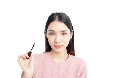白背景中使用睫毛膏的东方美女